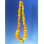 A CONTINUOUS STRING OF IRREGULAR GRADUATED ETHIOPIAN AMBER BEADS, PROBABLY FIRST HALF OF THE 20th C.