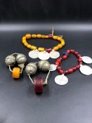 TWO STRANDS OF AMBER AND METAL DISC PEDANTS, TOGETHER WITH TWO FURTHER METAL LARGE BEADS AND AN