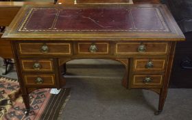 Edwardian inlaid mahogany desk^ gilt tooled red leather inset over seven drawers with short tapering