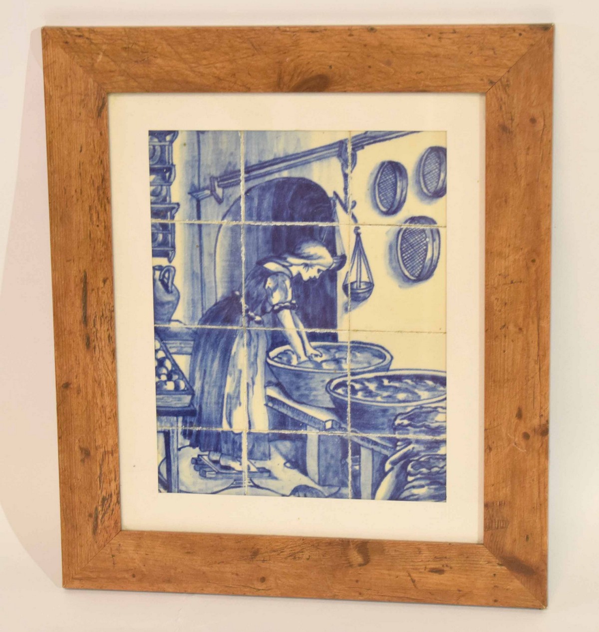 Two framed collections of small Delft tiles featuring a kitchen scene in wooden frame and further
