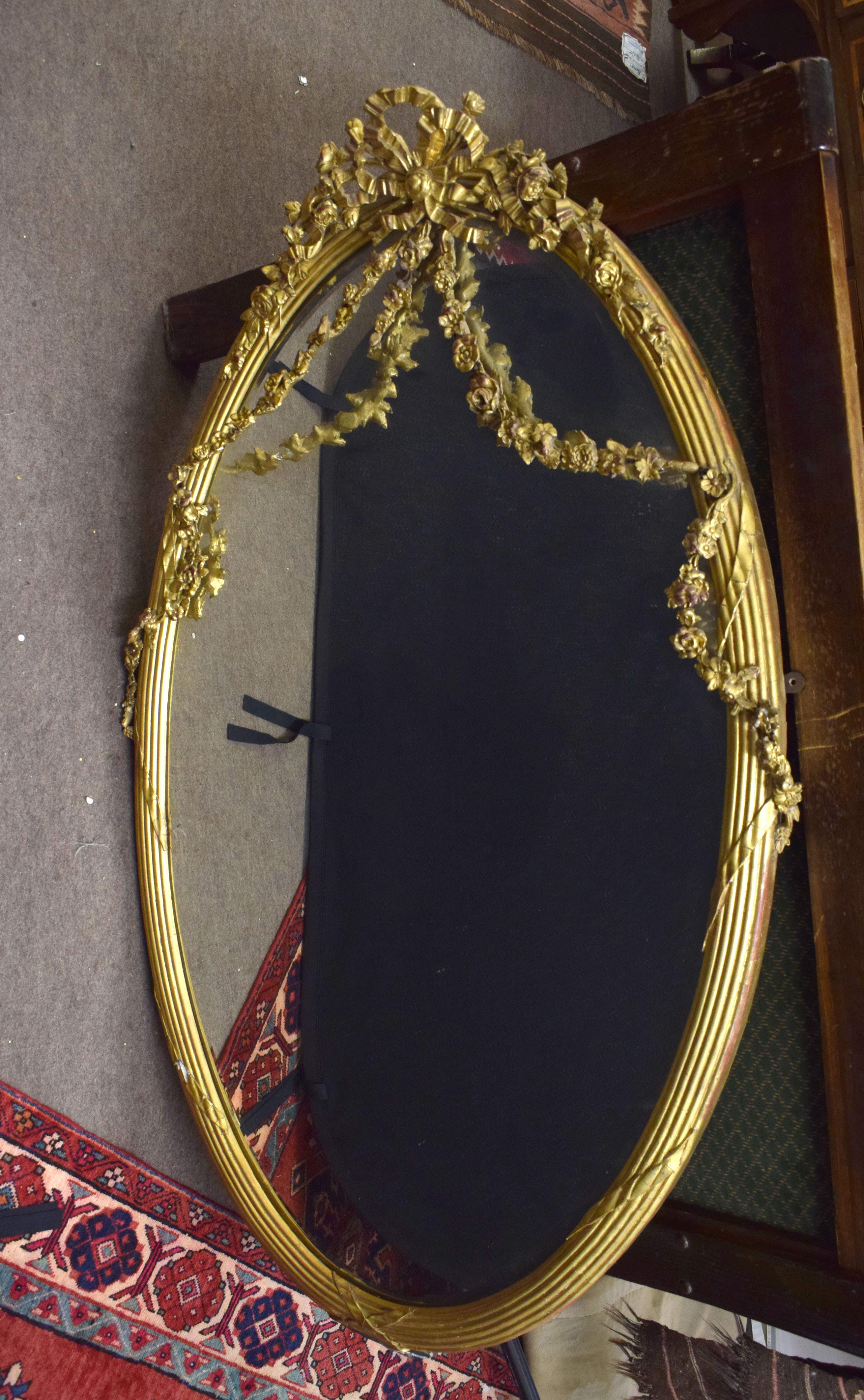 Large gilt and gesso oval wall mirror encrusted with gilt and gesso ribbon and floral swags^ 146cm