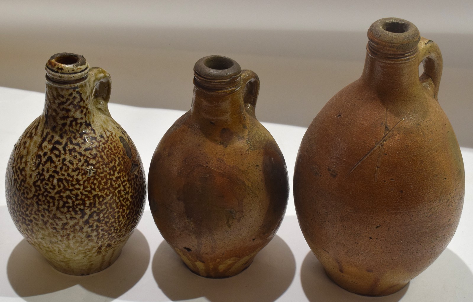 Group of three stoneware flagons^ 18th/19th century^ one with an orange peel type glaze (3)