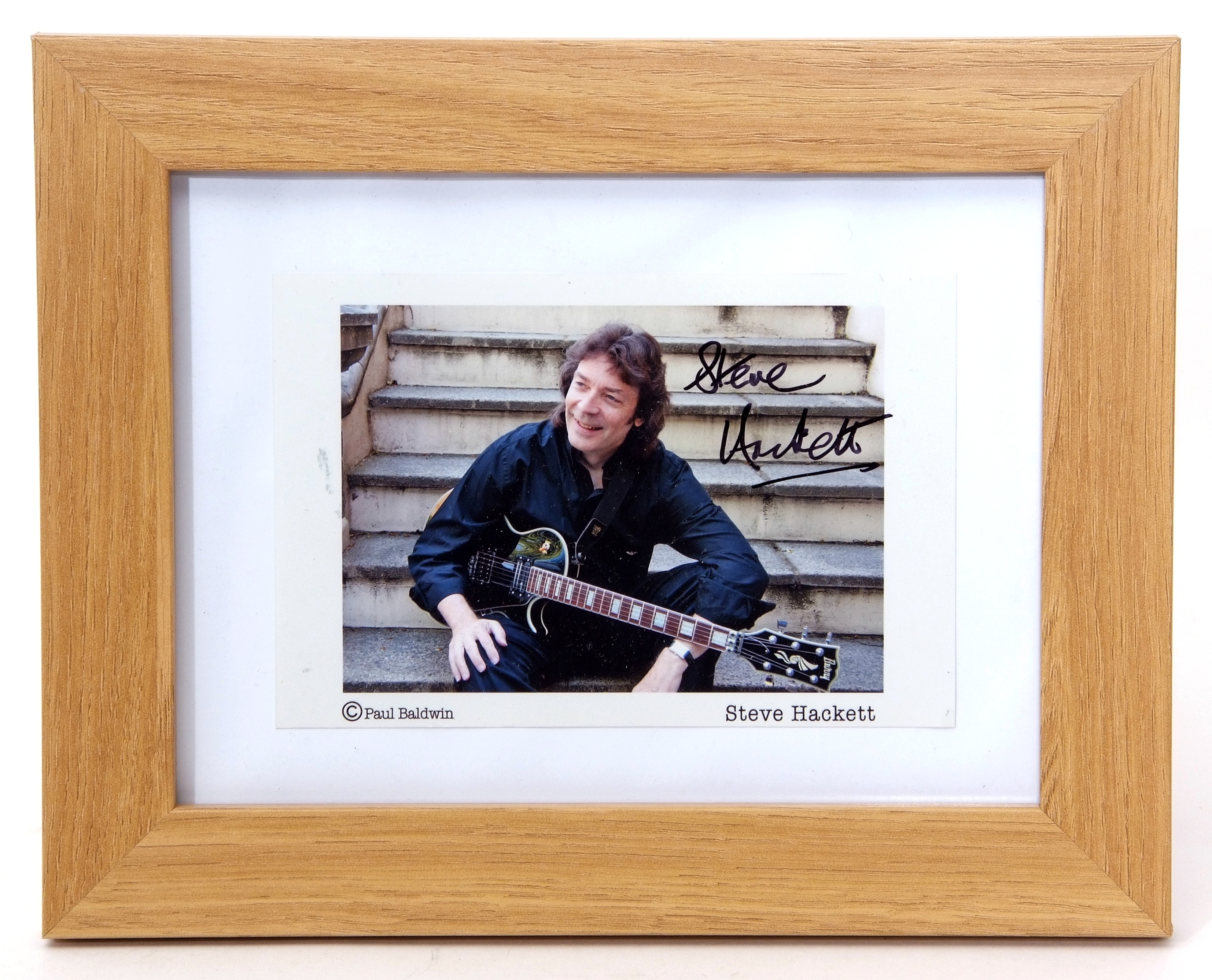 Photo of Steve Hackett in light oak frame, the photo signed by Hackett Note: sold on behalf of a