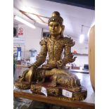 WOODEN CARVING OF A BUDDHA IN TYPICAL POSE, THE WOOD WITH PAINTED GILT DECORATION AND INLAID GLASS