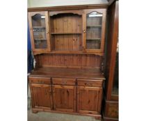 STAINED PINE DRESSER FITTED CENTRALLY WITH TWO SHELVES FLANKED EITHER SIDE WITH GLASS DOORS, THE