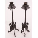 Pair of patinated bronze candlesticks, each with circular sconces, embossed with berries and foliage