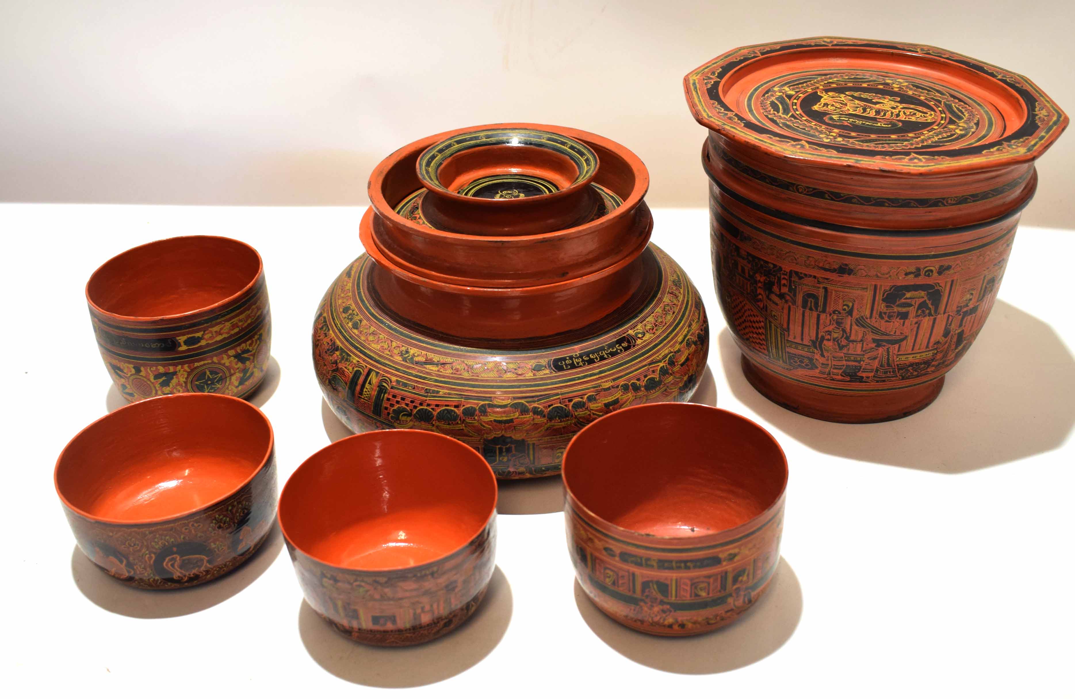 Group of Oriental red lacquer wares with various geometric and chinoiserie designs, comprising small