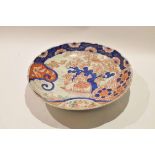 Large Japanese porcelain Imari dish with typical designs and a shaped rim, the underneath with