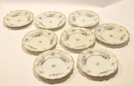 Group of eight French pottery plates decorated with a floral design within gilt borders, the