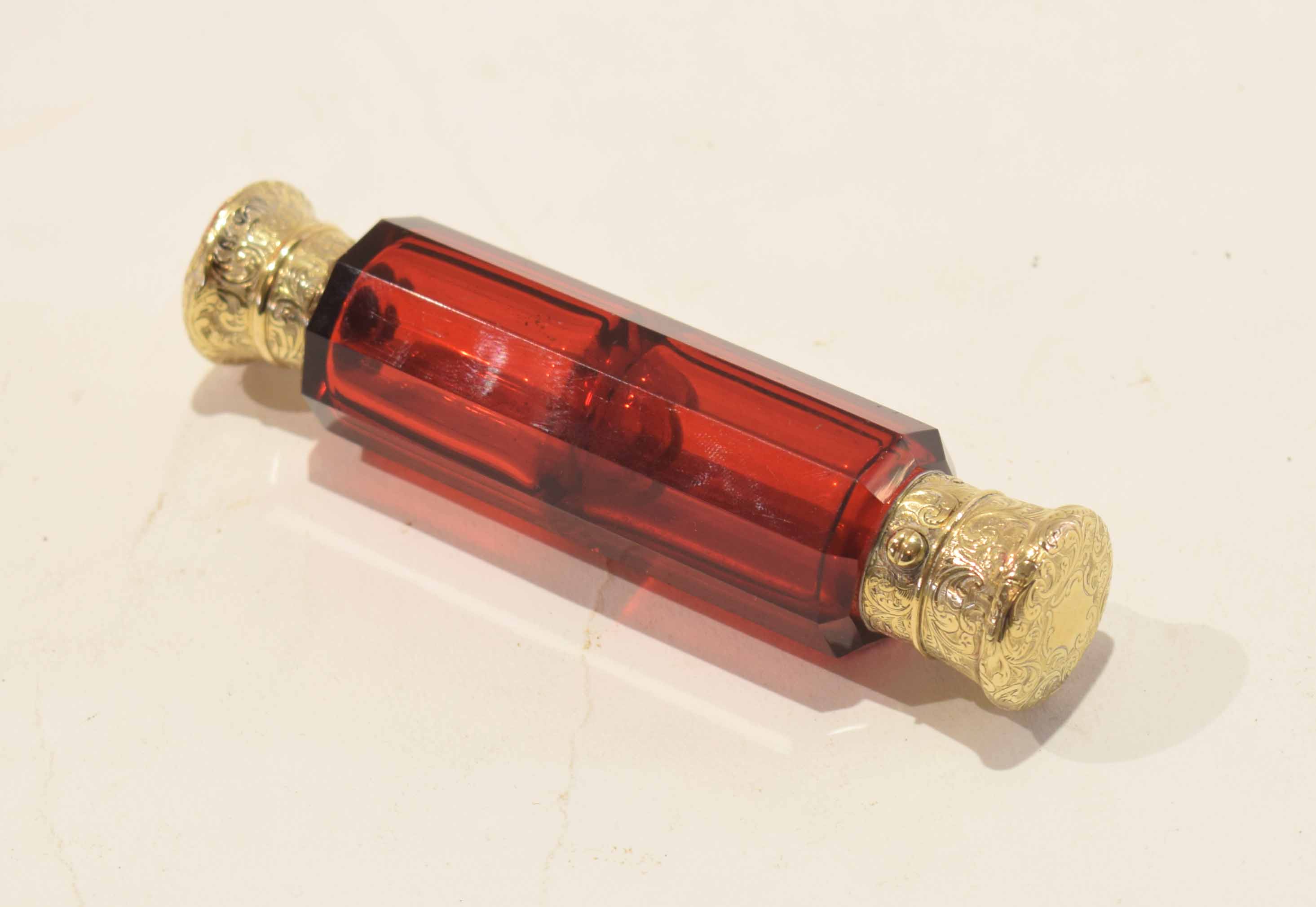 19th century ruby glass scent bottle of faceted form with gilt metal mounts and stopper, 12cm long