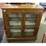 Mahogany and walnut inlaid bookcase with two glazed doors enclosing fitted shelving on peg feet,