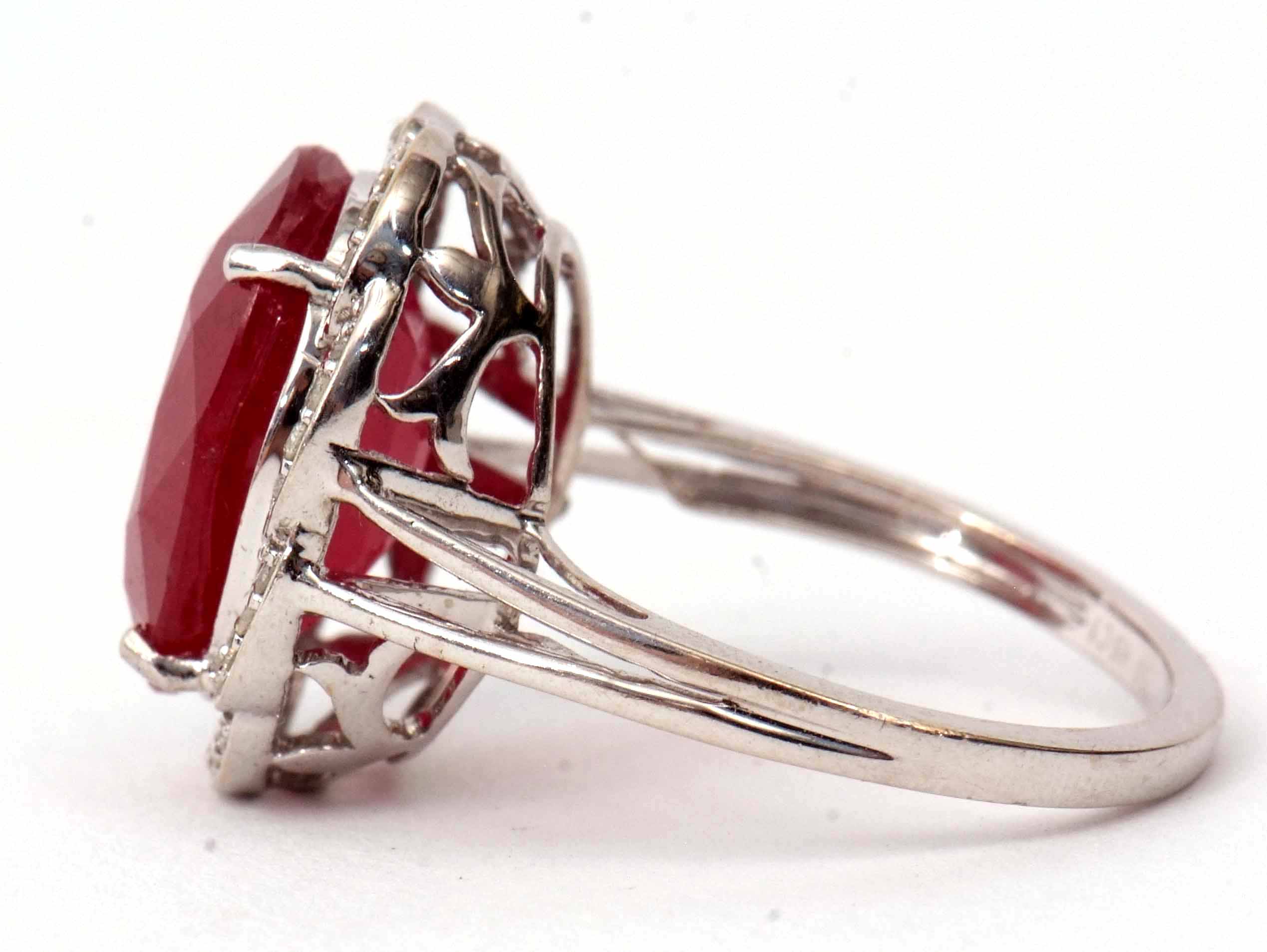 Modern ruby and diamond cluster ring, the oval faceted ruby 12 x 10mm, within a surround of small - Image 2 of 3