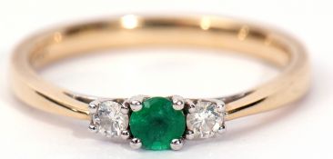 A 14K emerald and diamond ring centring a circular shaped small emerald flanked by two small