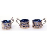 Set of three George V beaker holders of floral embossed and pierced circular form, having cast