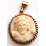 Antique carved ivory circular pendant, a symbolist portrait of Christ, framed in a later yellow