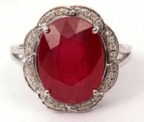 Modern ruby and diamond cluster ring, the oval faceted ruby 12 x 10mm, within a surround of small