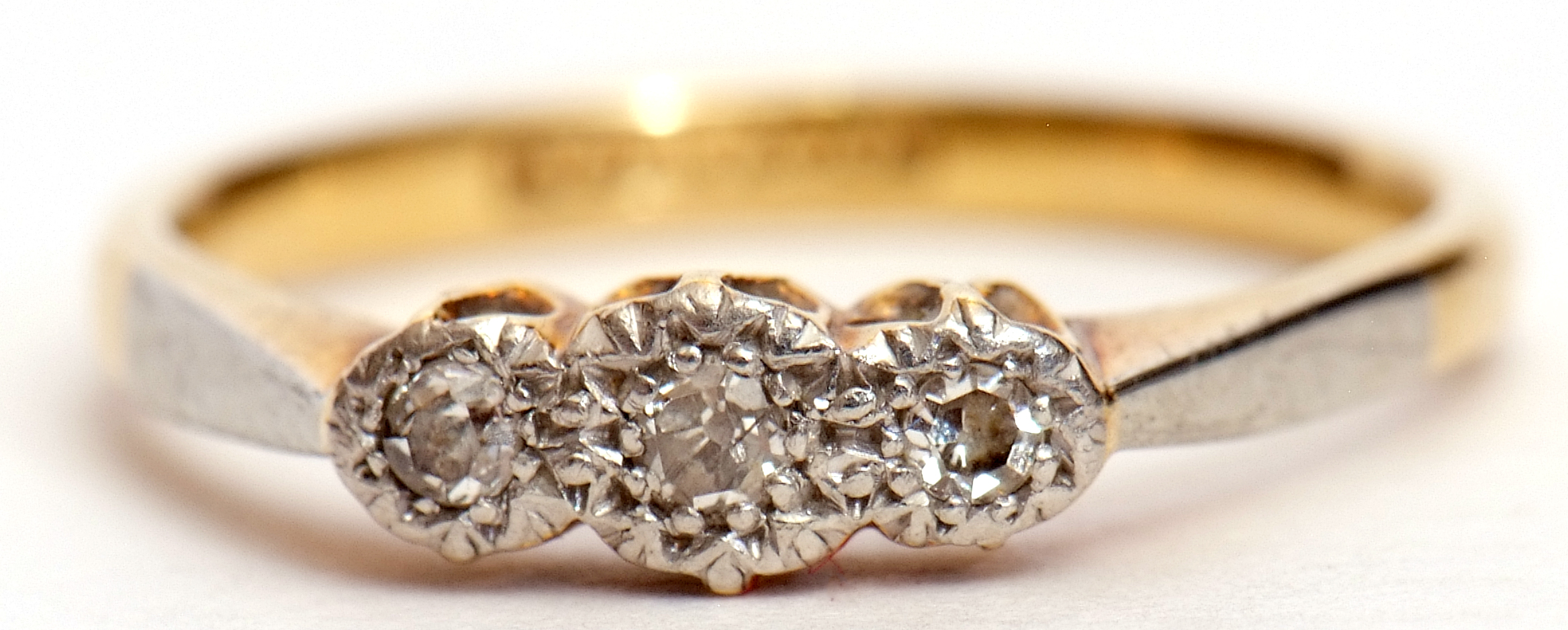 Precious metal three-stone diamond ring featuring 3 small single cut diamonds in a star engraved