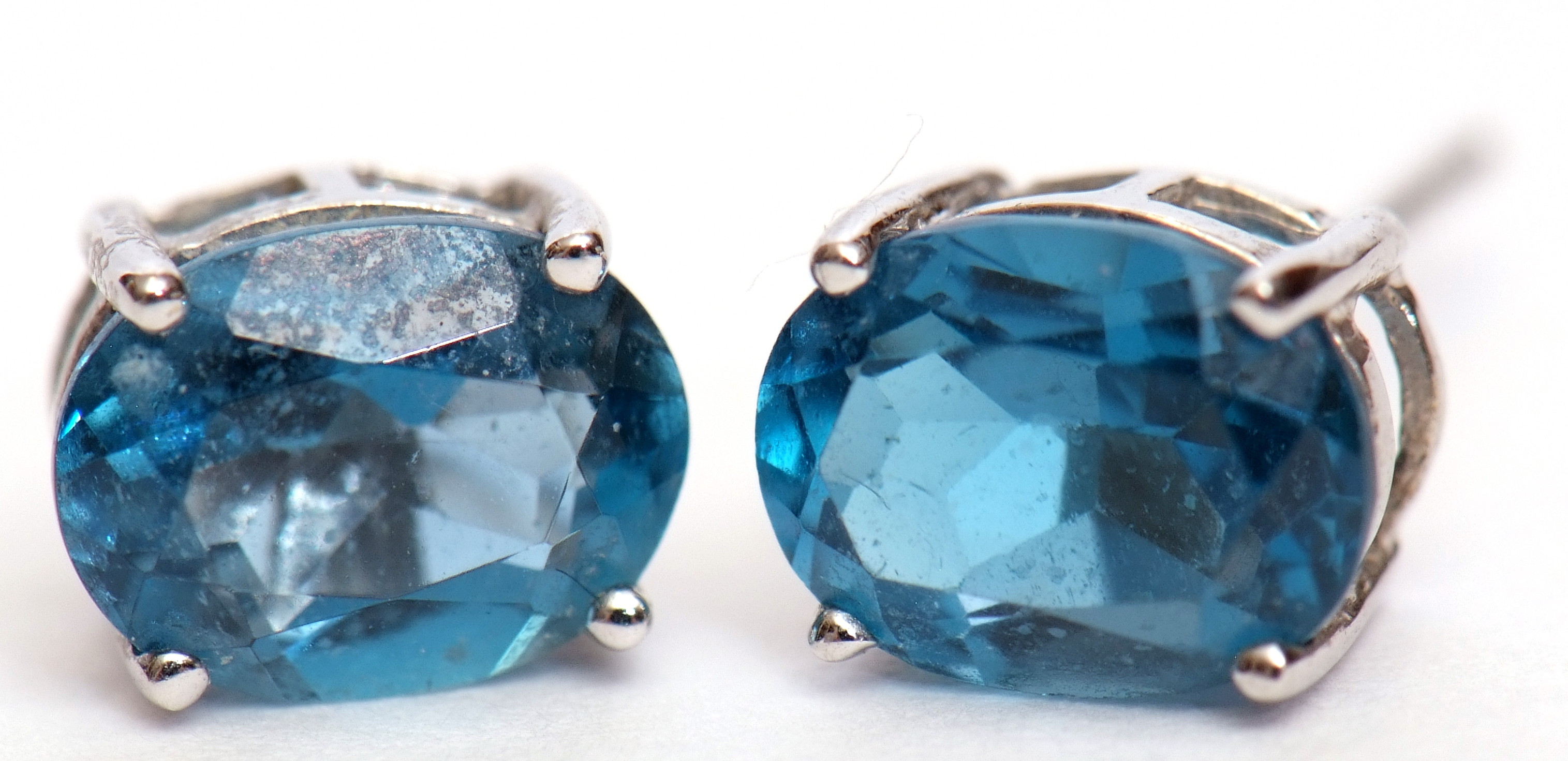 Pair of "London" blue topaz earrings, oval faceted shape, claw set in 9k stamped white mounts,