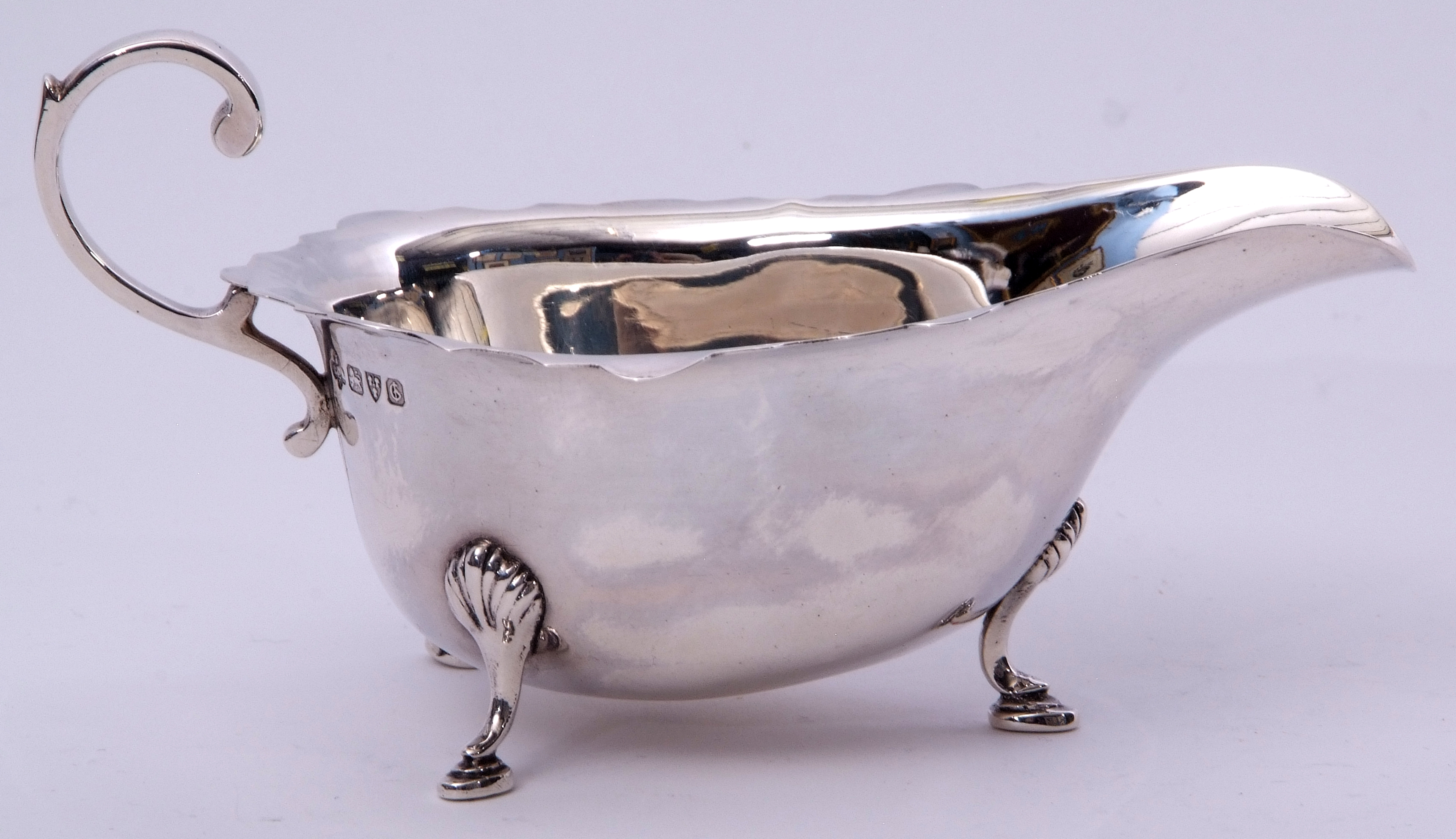 George V sauce boat in early Georgian style, having card cut rim, flying scrolled handle and