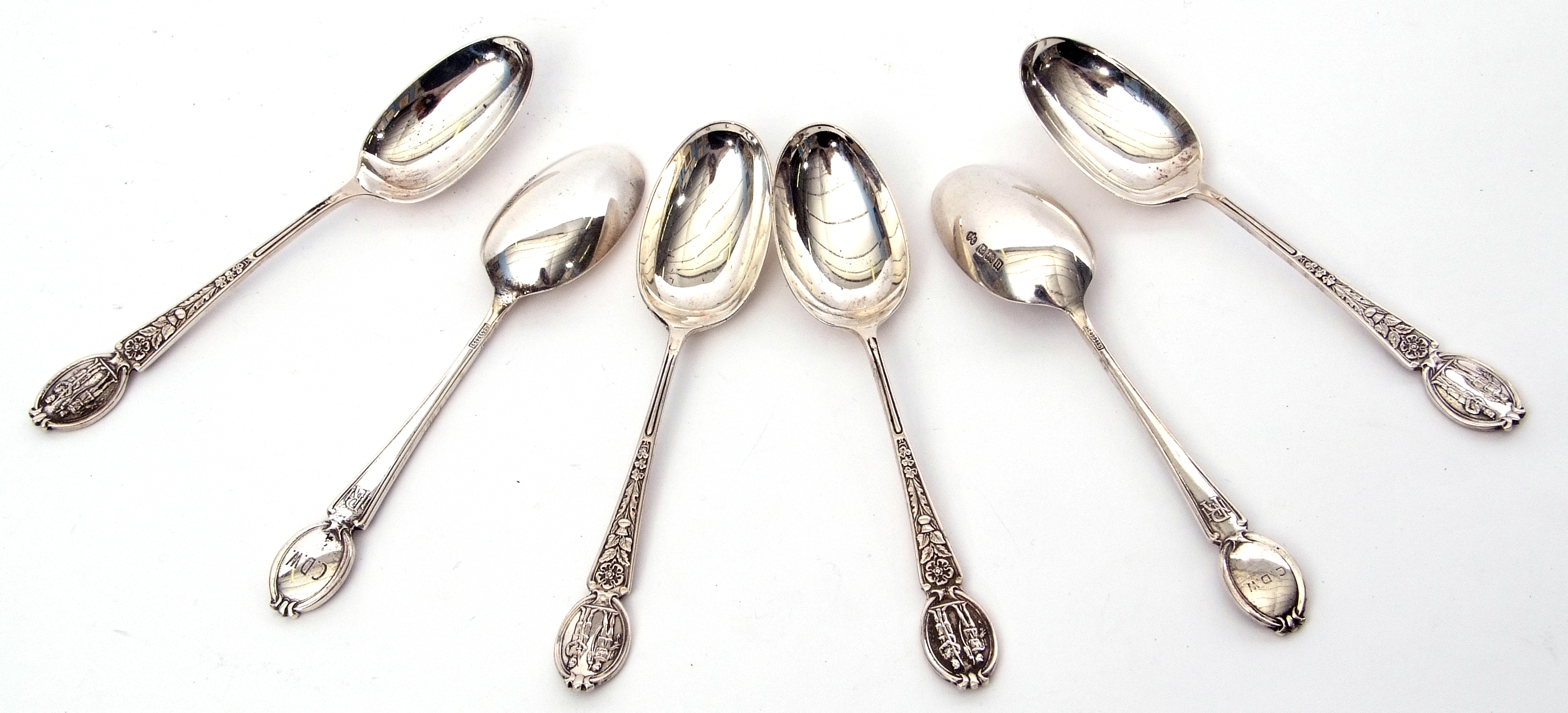 Set of six George V heavy tea spoons, the handles embossed with flowers and historic military