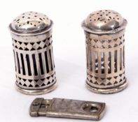 Small pair of George V pepperettes of pierced cylindrical form with bun top, one with clear glass