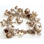 Hallmarked silver curb link bracelet suspending various white metal charms, 85.6gms gross weight