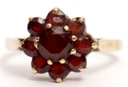 9ct stamped garnet cluster ring of flowerhead design, raised in a basket setting, size O