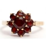 9ct stamped garnet cluster ring of flowerhead design, raised in a basket setting, size O