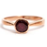 9ct stamped garnet single stone ring, the circular faceted garnet bezel set and raised in a plain