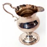 George III cream jug of inverted pear form, with card cut rim, leaf capped flying scrolled handle