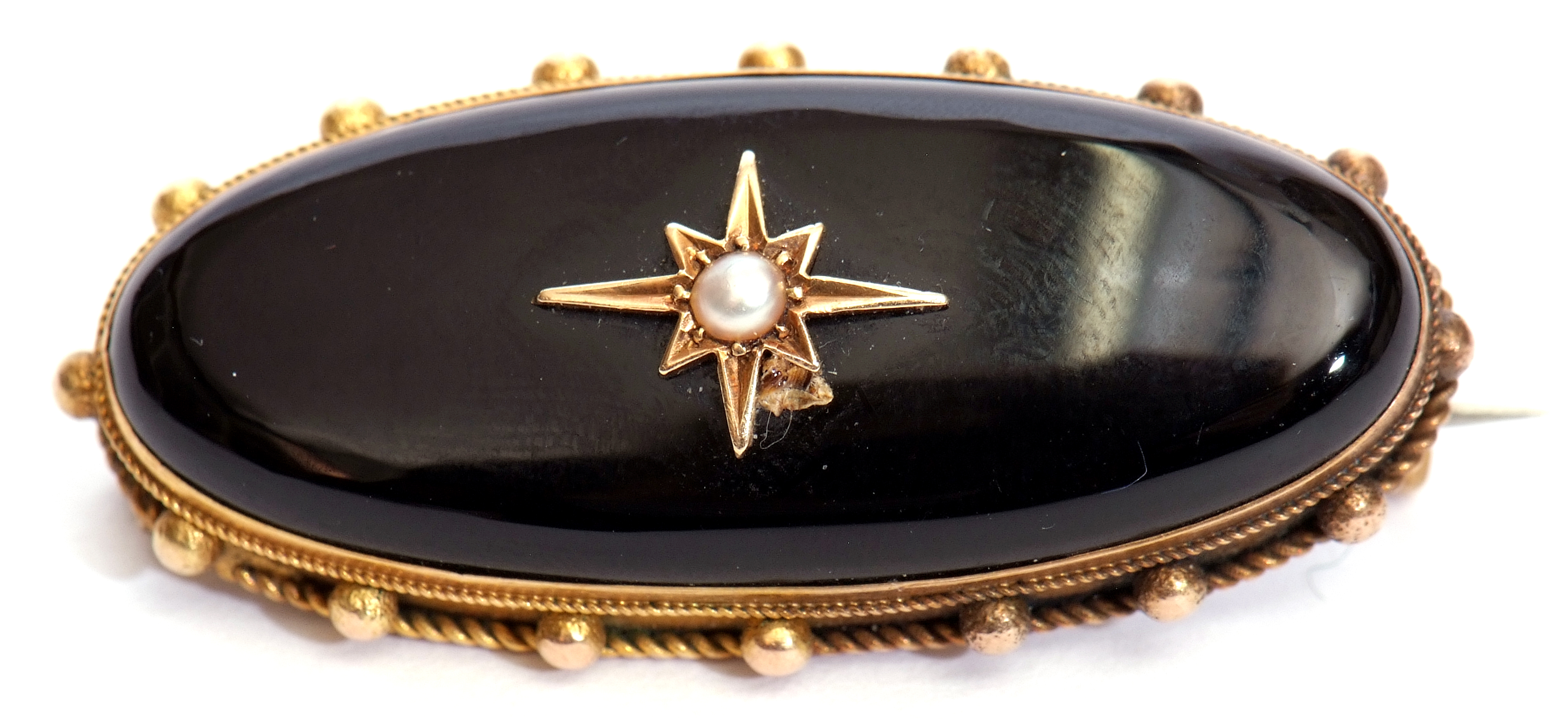 Victorian onyx and pearl set mourning brooch, the centre a pearl in a star engraved setting in an