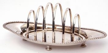 Late Victorian toast rack of six graduated hooped bars to a boat shaped base with gadrooned rim