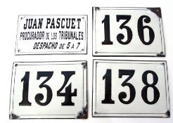 Group of enamel plaques with black lettering on white ground, one Spanish and three further