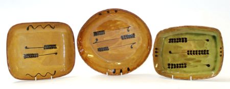 Set of three brown glazed goldstone pottery dishes with a slip design, largest 28cm diam (3)