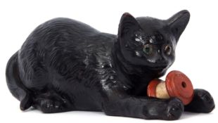 Unusual Bretby pottery model of a cat with glass eyes holding a reel of cotton in its forelegs, 24cm