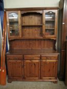 STAINED PINE DRESSER FITTED CENTRALLY WITH TWO SHELVES FLANKED EITHER SIDE WITH GLASS DOORS, THE