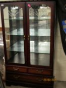 CHERRY WOOD TWO ENGRAVED DOOR DISPLAY CASE WITH TWO FULL WIDTH DRAWERS TO BASE, RAISED ON BRACKET