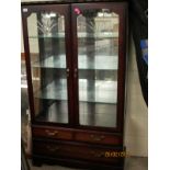 CHERRY WOOD TWO ENGRAVED DOOR DISPLAY CASE WITH TWO FULL WIDTH DRAWERS TO BASE, RAISED ON BRACKET