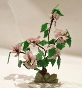Pottery model of a flower with green leaves, decorated in pink, standing on an onyx style base