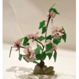 Pottery model of a flower with green leaves, decorated in pink, standing on an onyx style base