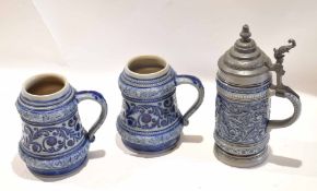 Group of three German stoneware pottery tankards with scrolling designs, one with pewter lid (3)