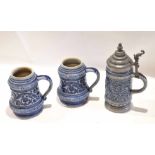 Group of three German stoneware pottery tankards with scrolling designs, one with pewter lid (3)