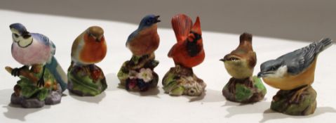 Group of six Royal Worcester birds on floral bases, including Blue Tit and a Robin, and a blue bird,