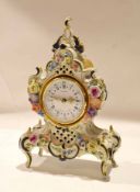 Porcelain clock case containing a clock, the dial picked out in Roman numerals with gilt hands,