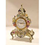 Porcelain clock case containing a clock, the dial picked out in Roman numerals with gilt hands,