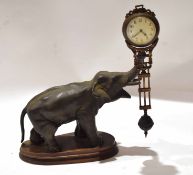 Bronzed metal mystery clock, modelled as an elephant with a clock balanced to its trunk, 31cm long