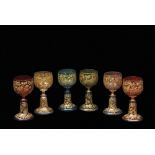 Group of six facon de venise wine glasses of various colours, all with a trailing floral gilt design