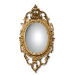 19th century gilt and gesso oval mirror with a scrolling open work surround and mounted with a