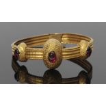 High grade yellow metal and garnet set bracelet, a design with three engraved oval shaped domes,