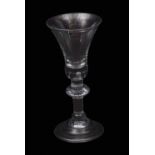 An important early 18th century heavy baluster wine glass with bell bowl with tiered solid base